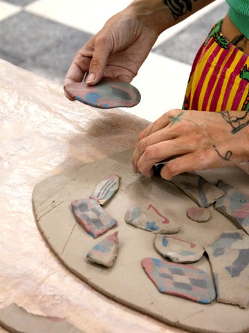 Person with tattoos creating ceramics by hand using manual techniques and nerikomi
