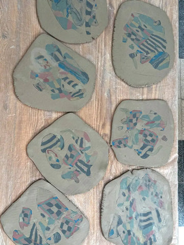 Set of hand-built clay coasters with abstract nerikomi designs on a wooden surface