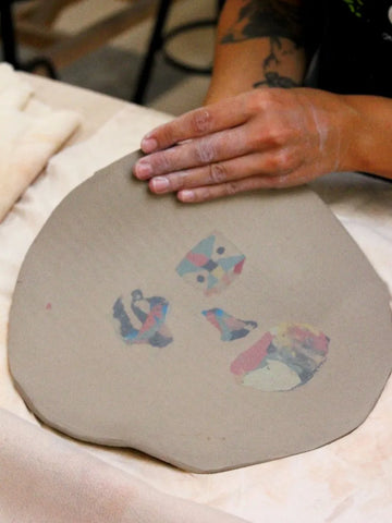 Person with tattoos creating ceramics by hand using manual techniques and nerikomi