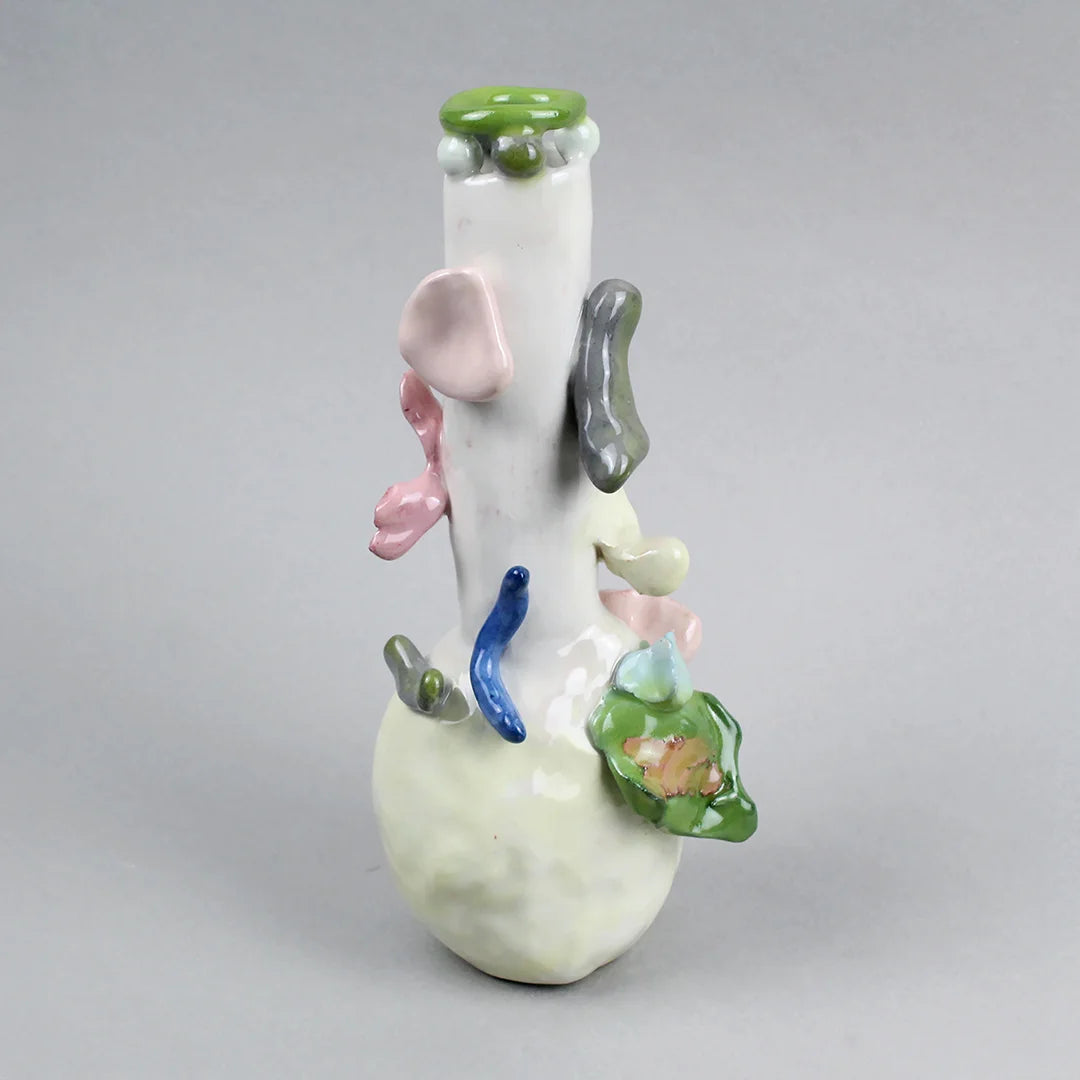 Hand-built decorative ceramic jar with organic, abstract forms and colourful details, made from earthenware and coloured earthenware, finished with a glossy transparent glaze. Created by artist Cíntia Coutinho, also known as Espirro, and photographed on a grey background.