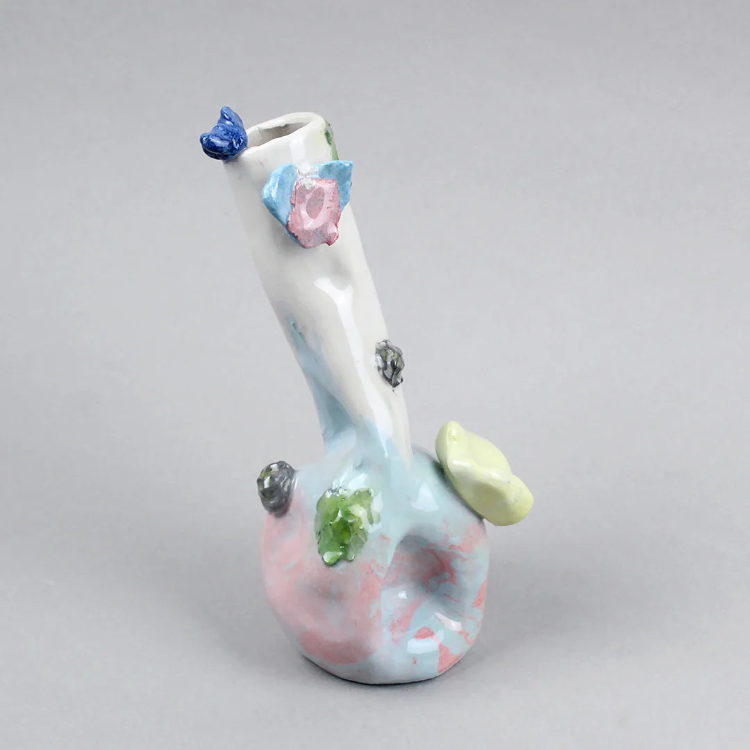 Hand-built decorative ceramic jar with organic, abstract forms and colourful details, made from earthenware and coloured earthenware, finished with a glossy transparent glaze. Created by artist Cíntia Coutinho, also known as Espirro, and photographed on a grey background.