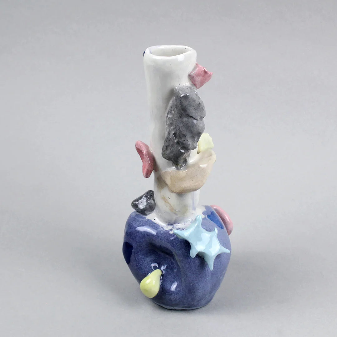 Hand-built decorative ceramic jar with organic, abstract forms and colourful details, made from earthenware and coloured earthenware, finished with a glossy transparent glaze. Created by artist Cíntia Coutinho, also known as Espirro, and photographed on a grey background.