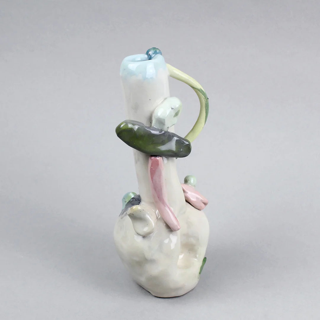 Hand-built decorative ceramic jar with organic, abstract forms and colourful details, made from earthenware and coloured earthenware, finished with a glossy transparent glaze. Created by artist Cíntia Coutinho, also known as Espirro, and photographed on a grey background.