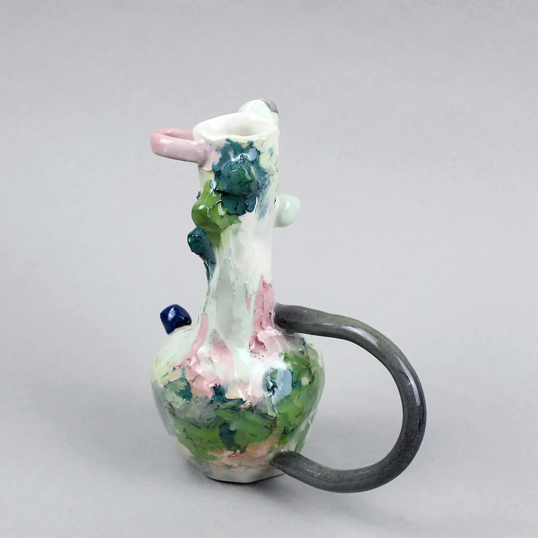 Hand-built decorative ceramic jar with organic, abstract forms and colourful details, made from earthenware and coloured earthenware, finished with a glossy transparent glaze. Created by artist Cíntia Coutinho, also known as Espirro, and photographed on a grey background.