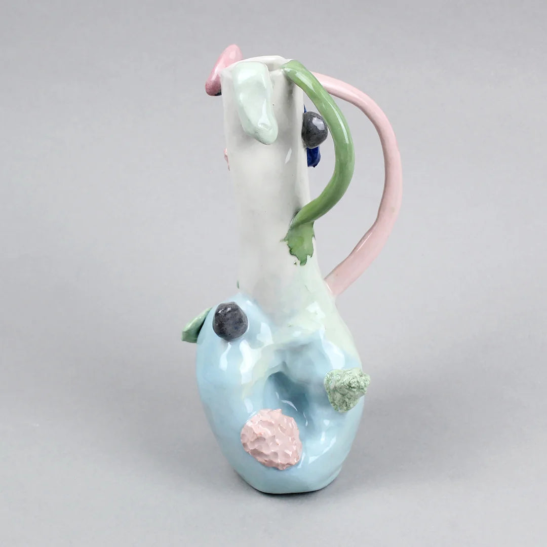 Hand-built decorative ceramic jar with organic, abstract forms and colourful details, made from earthenware and coloured earthenware, finished with a glossy transparent glaze. Created by artist Cíntia Coutinho, also known as Espirro, and photographed on a grey background.