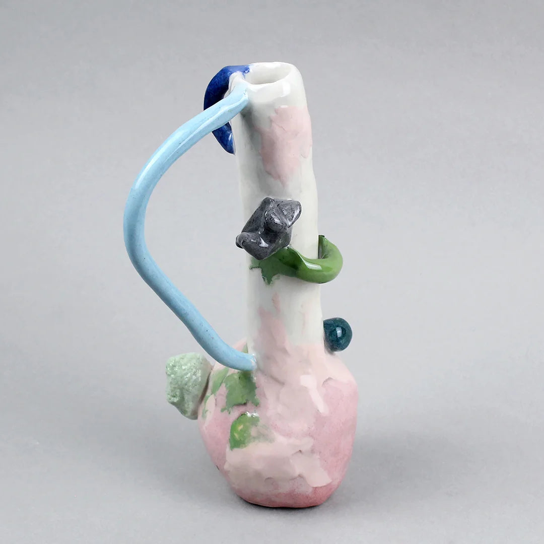 Hand-built decorative ceramic jar with organic, abstract forms and colourful details, made from earthenware and coloured earthenware, finished with a glossy transparent glaze. Created by artist Cíntia Coutinho, also known as Espirro, and photographed on a grey background.