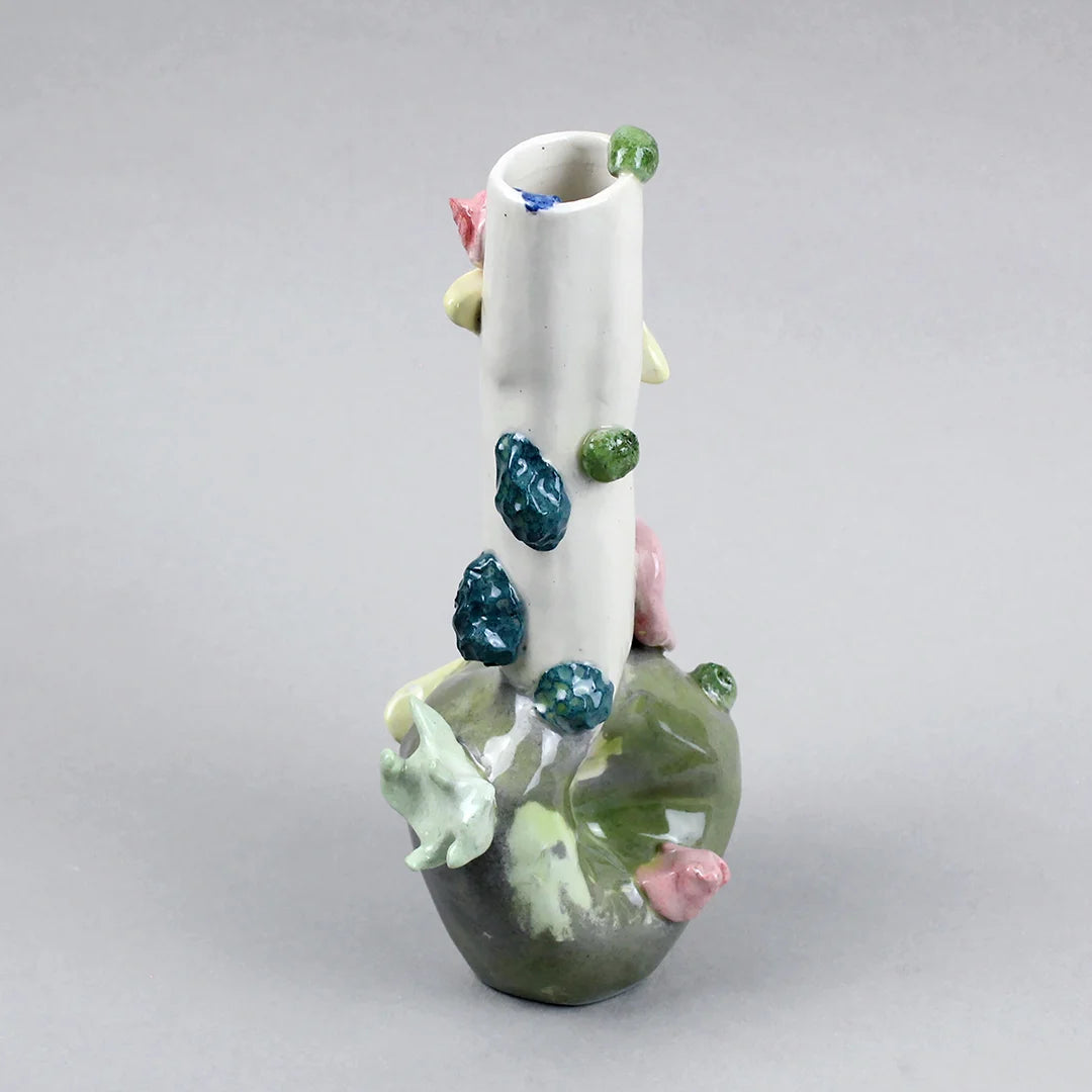 Hand-built decorative ceramic jar with organic, abstract forms and colourful details, made from earthenware and coloured earthenware, finished with a glossy transparent glaze. Created by artist Cíntia Coutinho, also known as Espirro, and photographed on a grey background.