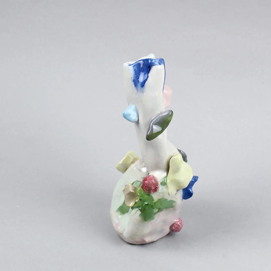 Hand-built decorative ceramic jar with organic, abstract forms and colourful details, made from earthenware and coloured earthenware, finished with a glossy transparent glaze. Created by artist Cíntia Coutinho, also known as Espirro, and photographed on a grey background.