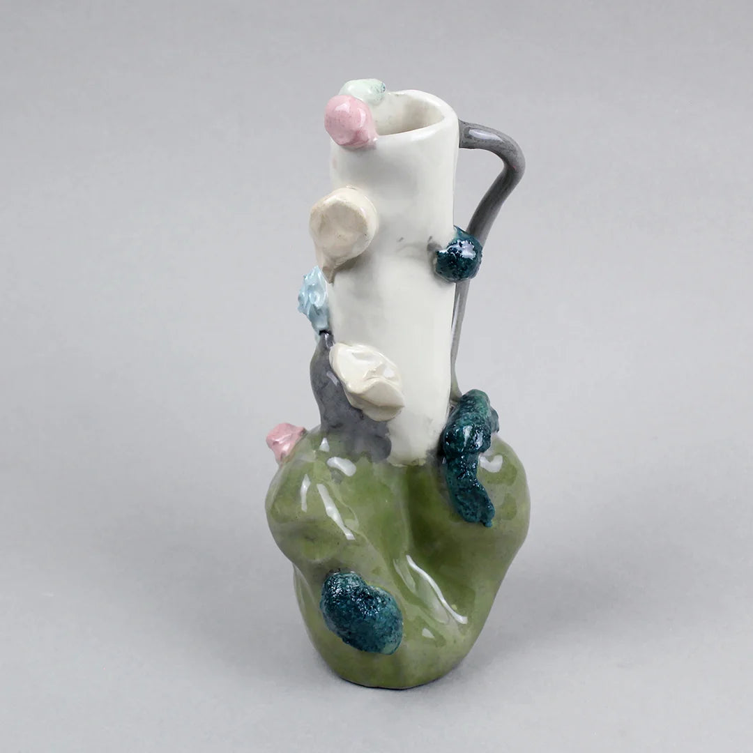 Hand-built decorative ceramic jar with organic, abstract forms and colourful details, made from earthenware and coloured earthenware, finished with a glossy transparent glaze. Created by artist Cíntia Coutinho, also known as Espirro, and photographed on a grey background.