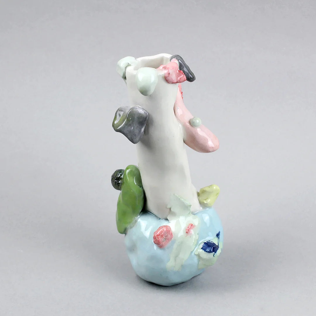 Hand-built decorative ceramic jar with organic, abstract forms and colourful details, made from earthenware and coloured earthenware, finished with a glossy transparent glaze. Created by artist Cíntia Coutinho, also known as Espirro, and photographed on a grey background.