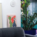 Sofa with a colorful rooster painting, potted plant, and turquoise cabinet in a room.