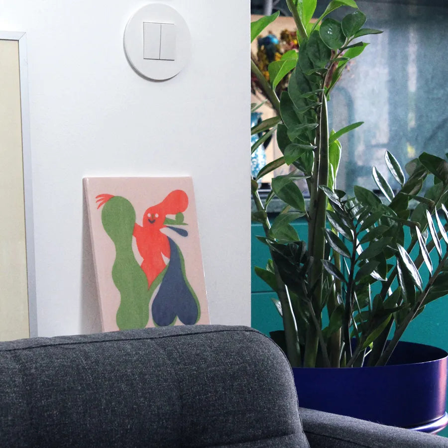 Sofa with a colorful rooster painting, potted plant, and turquoise cabinet in a room.