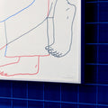Detail of a Manual screen print (50×70 cm) of an illustration showing two bodies embracing, drawn with fine linework on a white background. The figures extend almost to the edges of the paper, as if confined within its borders. The print is framed in a grey frame and hung on a Klein blue wall with matching blue metal bars.