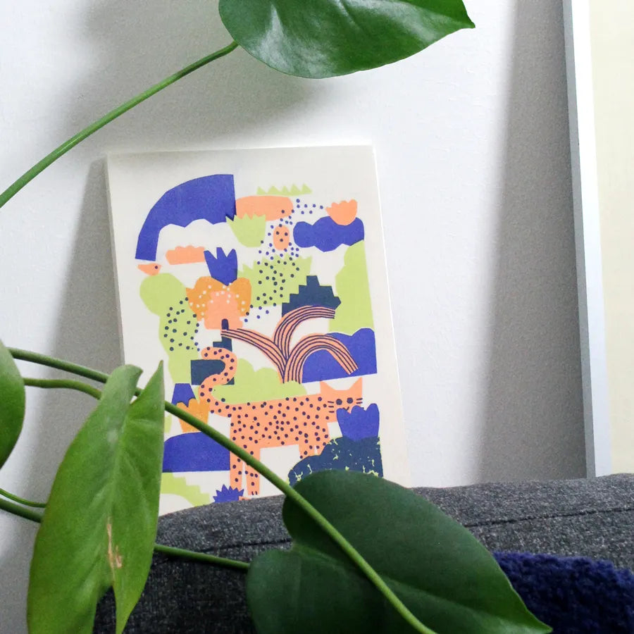 Tile with a colorful illustration on a wall with green leaves in the foreground