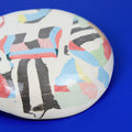 Hand-built decorative ceramic plate with organic, abstract forms and colourful details, made from earthenware and coloured earthenware, finished with a glossy transparent glaze. Created by artist Cíntia Coutinho, also known as Espirro.