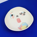 Hand-built decorative ceramic plate with organic, abstract forms and colourful details, made from earthenware and coloured earthenware, finished with a glossy transparent glaze. Created by artist Cíntia Coutinho, also known as Espirro.