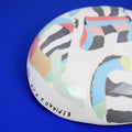 Hand-built decorative ceramic plate with organic, abstract forms and colourful details, made from earthenware and coloured earthenware, finished with a glossy transparent glaze. Created by artist Cíntia Coutinho, also known as Espirro.