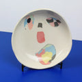Hand-built decorative ceramic plate with organic, abstract forms and colourful details, made from earthenware and coloured earthenware, finished with a glossy transparent glaze. Created by artist Cíntia Coutinho, also known as Espirro.