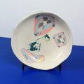 Hand-built decorative ceramic deep plate with organic, abstract forms and colourful details, made from earthenware and coloured earthenware, finished with a glossy transparent glaze. Created by artist Cíntia Coutinho, also known as Espirro.