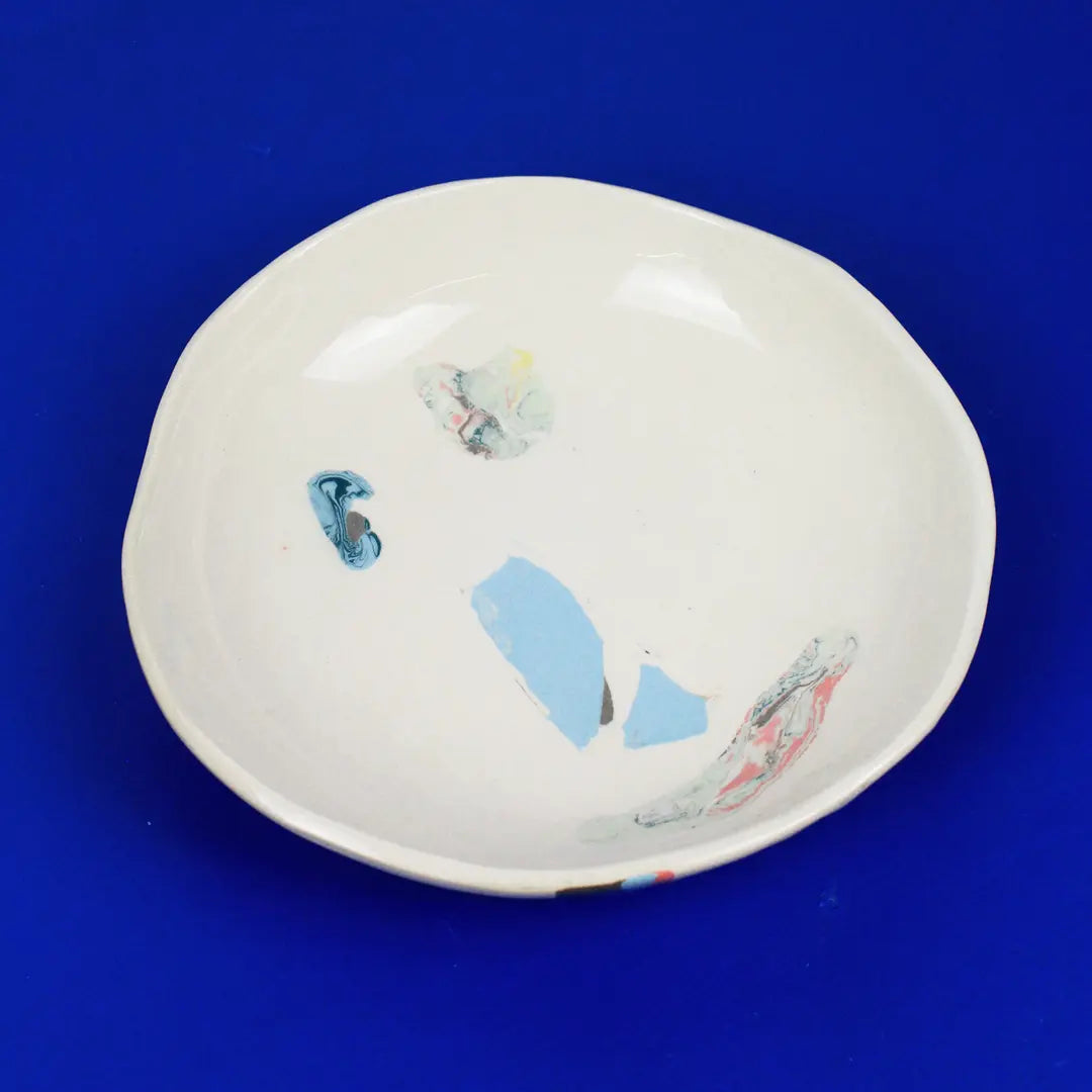 Hand-built decorative ceramic deep plate with organic, abstract forms and colourful details, made from earthenware and coloured earthenware, finished with a glossy transparent glaze. Created by artist Cíntia Coutinho, also known as Espirro.