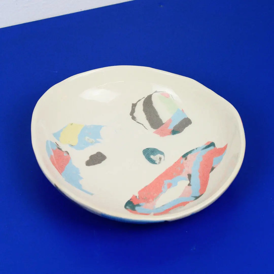 Hand-built decorative ceramic plate with organic, abstract forms and colourful details, made from earthenware and coloured earthenware, finished with a glossy transparent glaze. Created by artist Cíntia Coutinho, also known as Espirro.