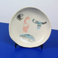 Hand-built decorative ceramic deep plate with organic, abstract forms and colourful details, made from earthenware and coloured earthenware, finished with a glossy transparent glaze. Created by artist Cíntia Coutinho, also known as Espirro.