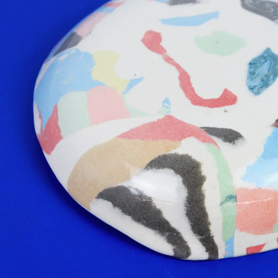 Hand-built decorative ceramic deep plate with organic, abstract forms and colourful details, made from earthenware and coloured earthenware, finished with a glossy transparent glaze. Created by artist Cíntia Coutinho, also known as Espirro.