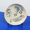 Hand-built decorative ceramic deep plate with organic, abstract forms and colourful details, made from earthenware and coloured earthenware, finished with a glossy transparent glaze. Created by artist Cíntia Coutinho, also known as Espirro.