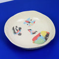 Hand-built decorative ceramic deep plate with organic, abstract forms and colourful details, made from earthenware and coloured earthenware, finished with a glossy transparent glaze. Created by artist Cíntia Coutinho, also known as Espirro.