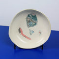 Hand-built decorative ceramic deep plate with organic, abstract forms and colourful details, made from earthenware and coloured earthenware, finished with a glossy transparent glaze. Created by artist Cíntia Coutinho, also known as Espirro.