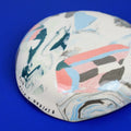 Hand-built decorative ceramic deep plate with organic, abstract forms and colourful details, made from earthenware and coloured earthenware, finished with a glossy transparent glaze. Created by artist Cíntia Coutinho, also known as Espirro.