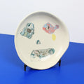 Hand-built decorative ceramic deep plate with organic, abstract forms and colourful details, made from earthenware and coloured earthenware, finished with a glossy transparent glaze. Created by artist Cíntia Coutinho, also known as Espirro.