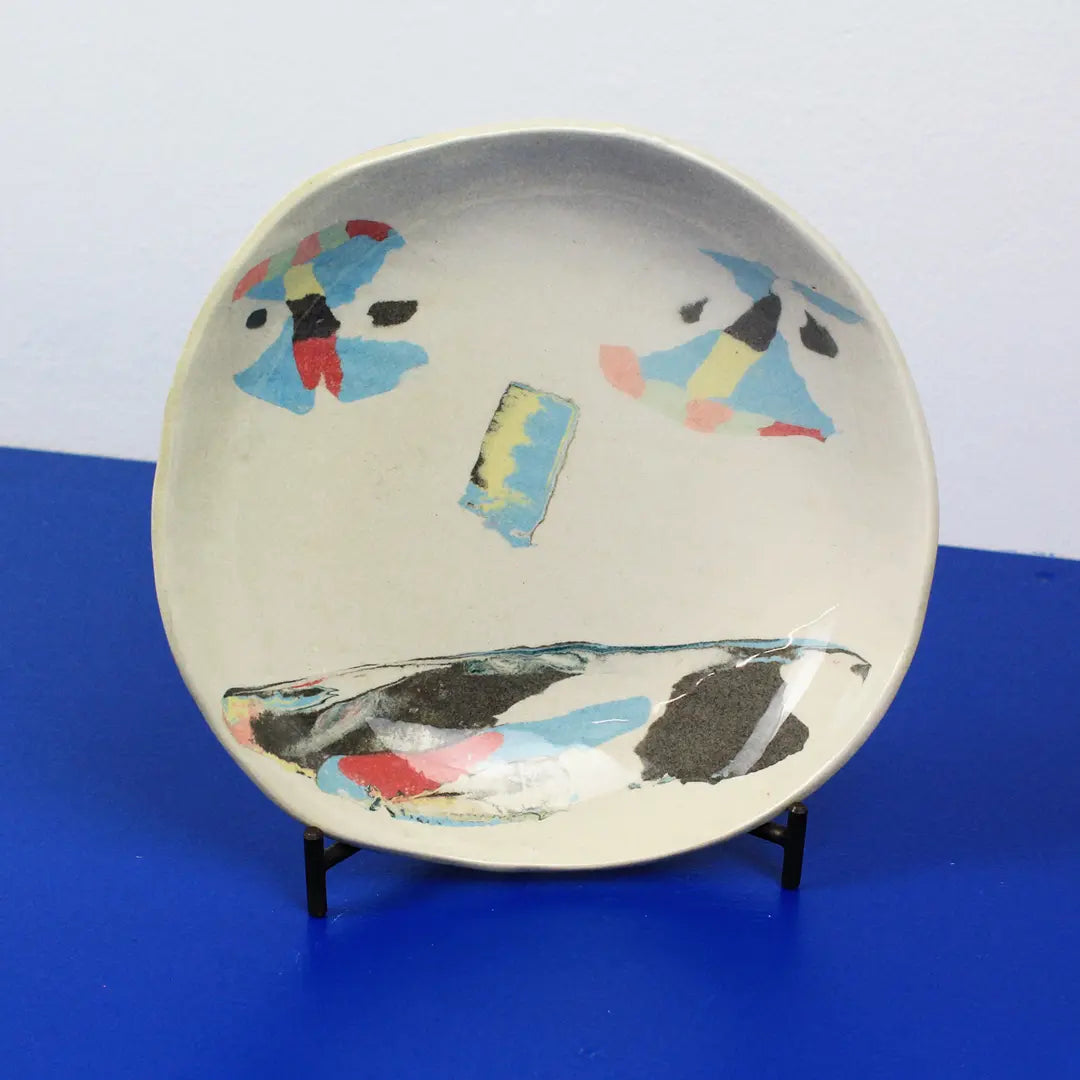Hand-built decorative ceramic deep plate with organic, abstract forms and colourful details, made from earthenware and coloured earthenware, finished with a glossy transparent glaze. Created by artist Cíntia Coutinho, also known as Espirro.
