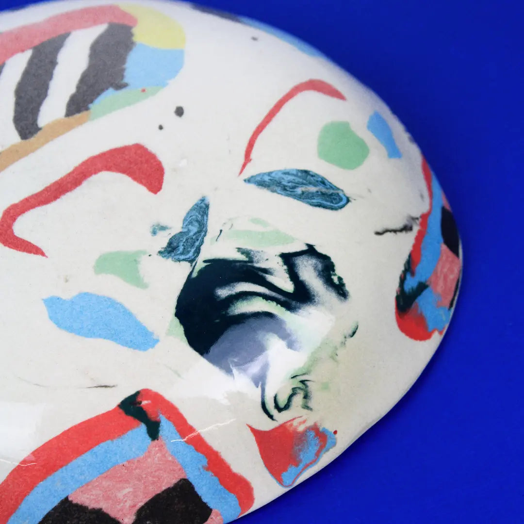 Hand-built decorative ceramic deep plate with organic, abstract forms and colourful details, made from earthenware and coloured earthenware, finished with a glossy transparent glaze. Created by artist Cíntia Coutinho, also known as Espirro.