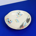 Hand-built decorative ceramic deep plate with organic, abstract forms and colourful details, made from earthenware and coloured earthenware, finished with a glossy transparent glaze. Created by artist Cíntia Coutinho, also known as Espirro.