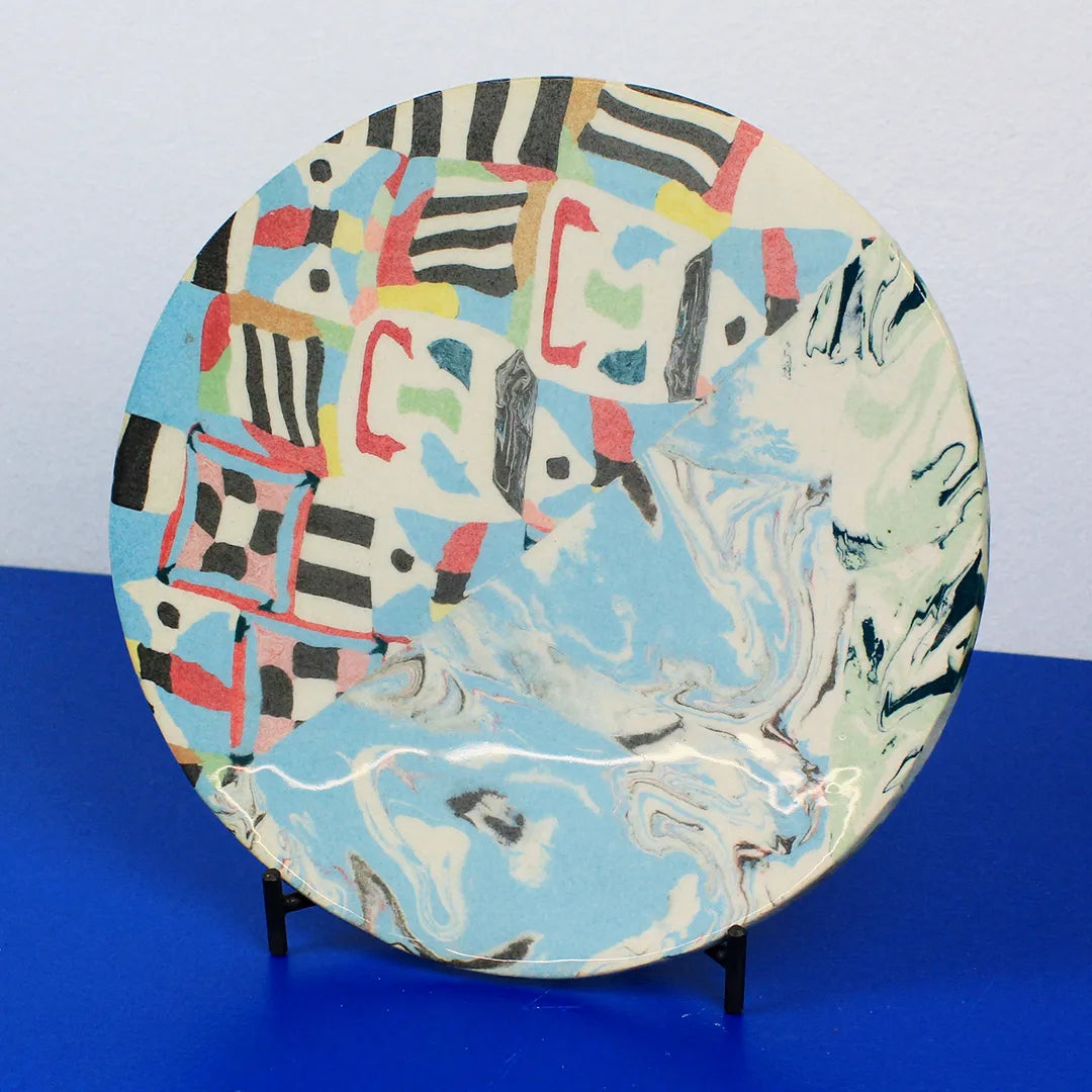 Hand-built decorative ceramic flat plate with organic, abstract forms and colourful details, made from earthenware and coloured earthenware, finished with a glossy transparent glaze. Created by artist Cíntia Coutinho, also known as Espirro.