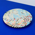Hand-built decorative ceramic flat plate with organic, abstract forms and colourful details, made from earthenware and coloured earthenware, finished with a glossy transparent glaze. Created by artist Cíntia Coutinho, also known as Espirro.