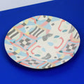 Hand-built decorative ceramic plate with organic, abstract forms and colourful details, made from earthenware and coloured earthenware, finished with a glossy transparent glaze. Created by artist Cíntia Coutinho, also known as Espirro.