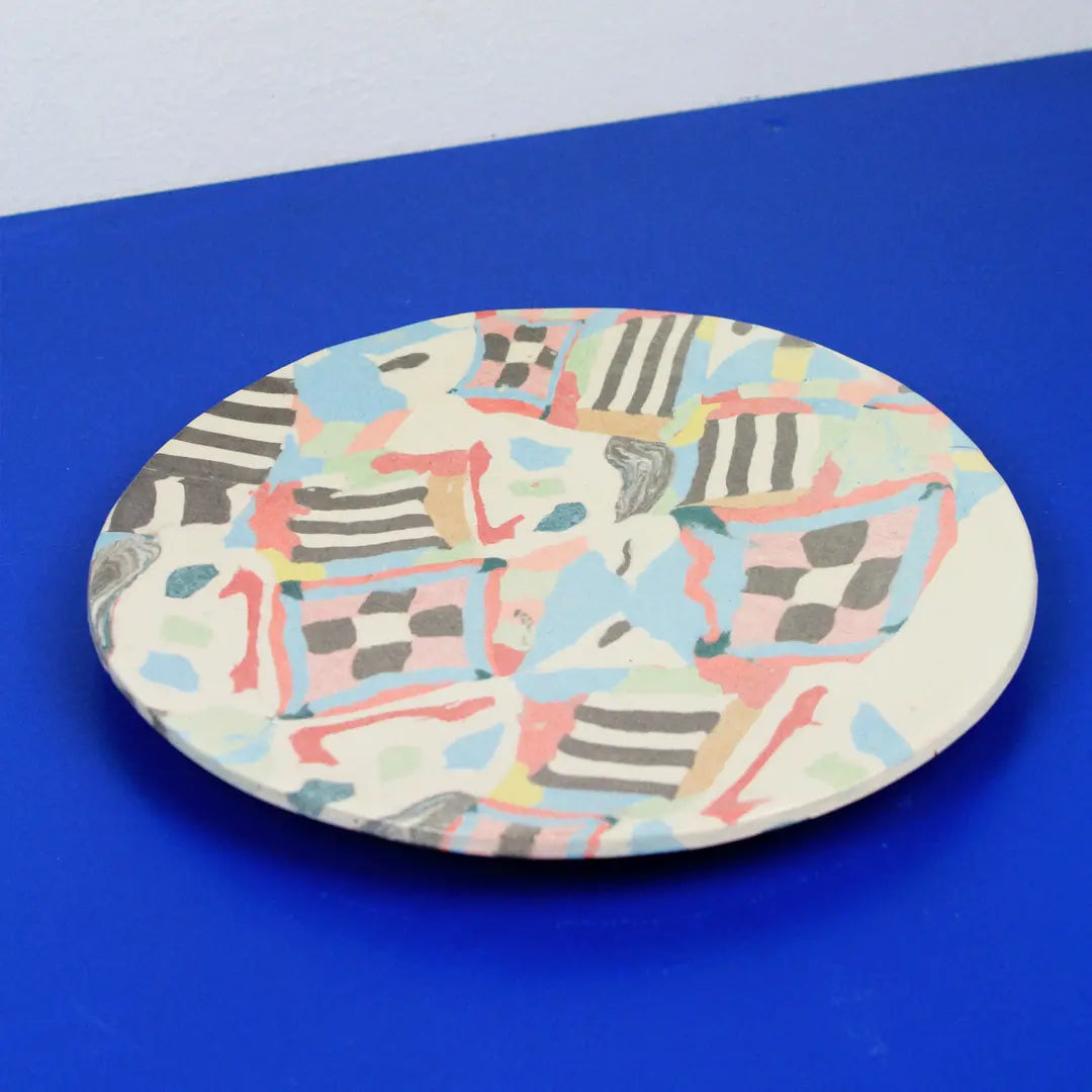 Hand-built decorative ceramic plate with organic, abstract forms and colourful details, made from earthenware and coloured earthenware, finished with a glossy transparent glaze. Created by artist Cíntia Coutinho, also known as Espirro.
